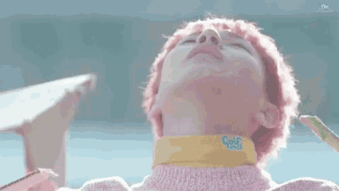 a close up of a person with pink hair wearing a pink sweater and a yellow collar .
