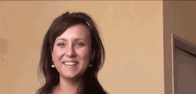 a woman wearing a headband and earrings is smiling .