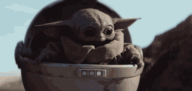 a baby yoda is sitting in a helmet with a button that says 000 on it