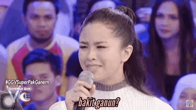 a woman is crying while holding a microphone and says bakit ganun .