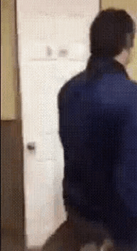 a man in a blue jacket is standing in front of a door .