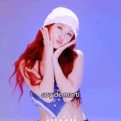 a woman with red hair is wearing a white beanie and has the words soy de marti written on her face