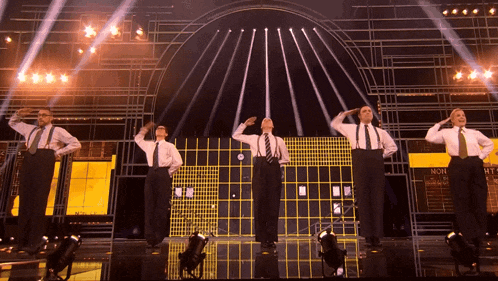 a group of men salute on a stage with a sign that says non