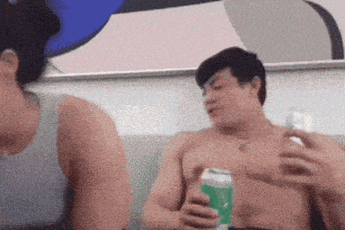 a shirtless man is holding a green can of soda