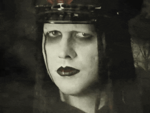 a black and white photo of a woman 's face with red lips and a hat on .