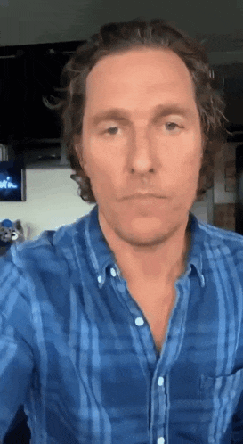 a man in a blue plaid shirt is making a face .