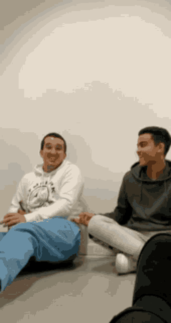 two men sitting on the floor with their legs crossed