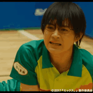 a man wearing glasses and a green and yellow shirt has a sticker on his shirt that says ' 2017 ' on it