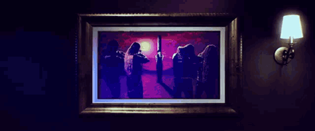 a framed painting of a group of people standing in front of a sunset