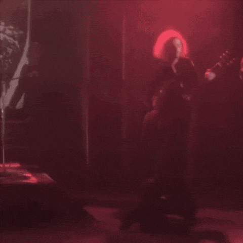 a man is kneeling down while another man plays a guitar on stage