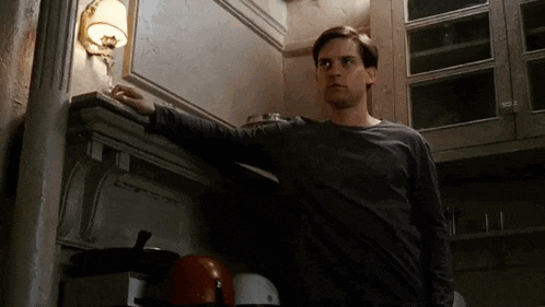 a man in a black shirt is standing in a kitchen