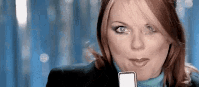 a woman is holding a cell phone in her hand and making a face .