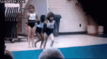 a group of young girls are jumping into a swimming pool .