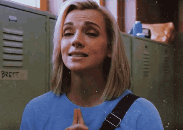 a woman in a blue shirt stands in front of a locker that says brett
