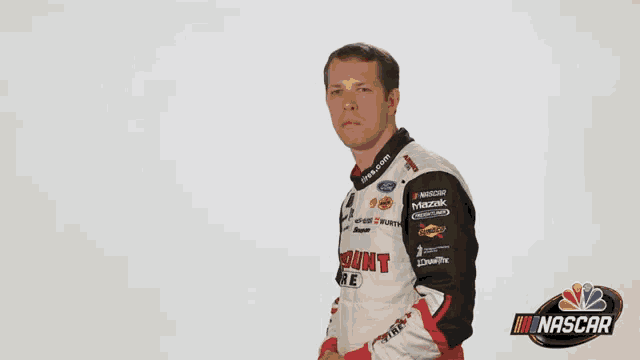 a man in a nascar jacket stands in front of a nbc logo