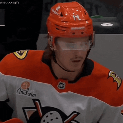 a hockey player wearing an anaheim jersey and a red helmet