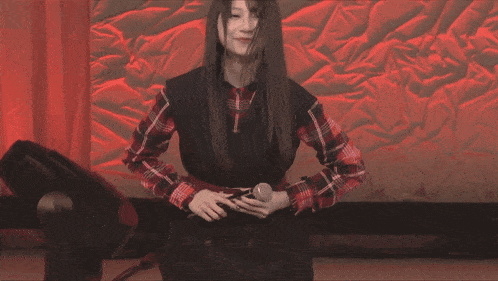 a woman in a plaid shirt is holding a microphone and smiling