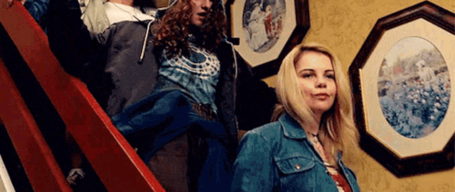 two women are standing on a set of stairs in front of framed pictures