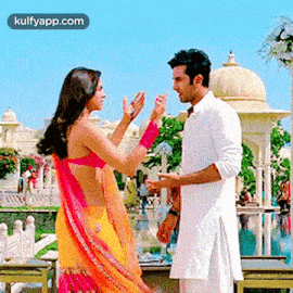 a man and a woman are standing next to each other in front of a building and talking to each other .
