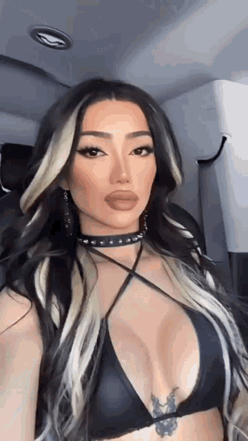 a woman in a black bikini top is taking a selfie while sitting in a car .