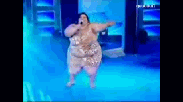 a woman is singing into a microphone on a stage with a blue background that says ' guigui ' on it