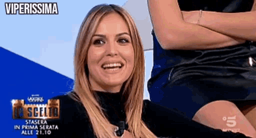a woman is smiling in front of a sign that says ' viperissima ' on it