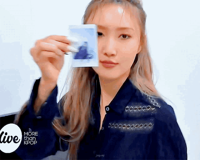 a woman is holding a polaroid picture in front of her face with the words more than kpop in the background
