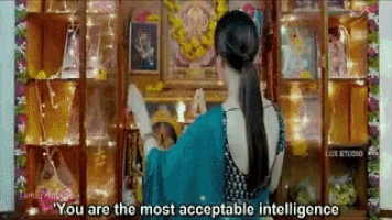 a woman in a blue saree is standing in front of a temple and says `` you are the most acceptable intelligence '' .