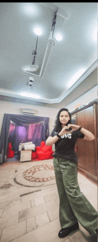 a woman wearing a black shirt that says jvc is standing in a room
