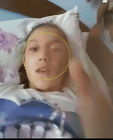 a girl with a yellow circle around her face is laying in bed
