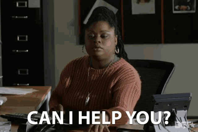 a woman sitting at a desk with the words can i help you on the bottom