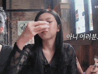a woman wipes her nose in front of a sign that says ' malt ' on it