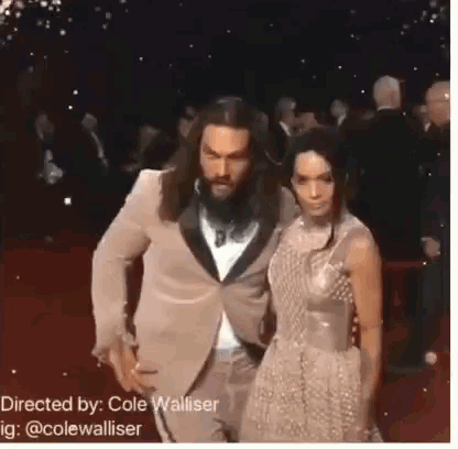a man and a woman are walking on a red carpet .