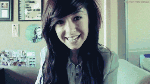 a girl is smiling in front of a wall with pictures on it and the words grimmiebrasil on the bottom