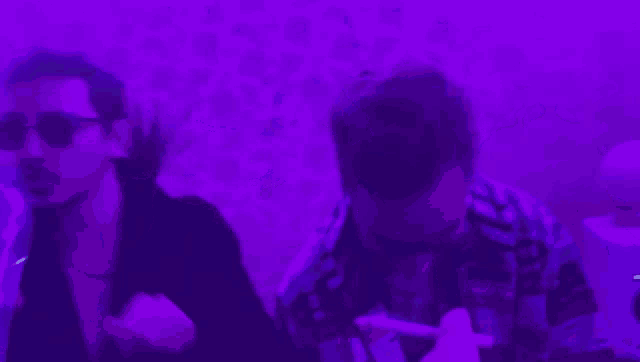 a man is drinking water from a plastic bottle in a purple room .