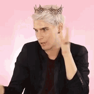 a man wearing a black jacket and a crown on his head is making a peace sign .