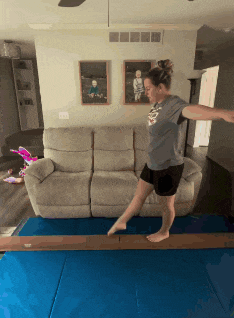 a woman balances on a balance beam in a living room