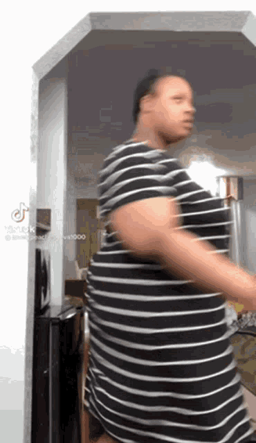 a woman in a black and white striped dress is dancing in a living room .