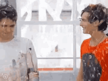 two young men are standing next to each other in front of a window covered in bubbles .