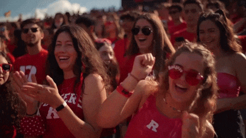a group of people wearing red shirts with the letter r on them are standing in a crowd .