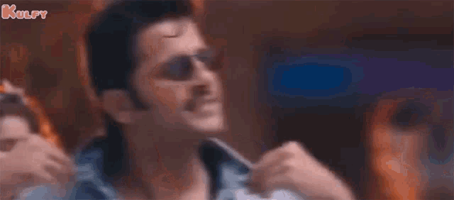 a man wearing sunglasses is dancing in front of a crowd of people .