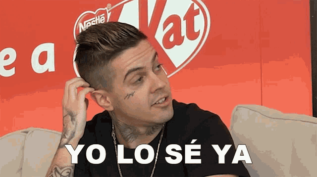 a man with a tattoo on his face is sitting on a couch and says yo lo se ya