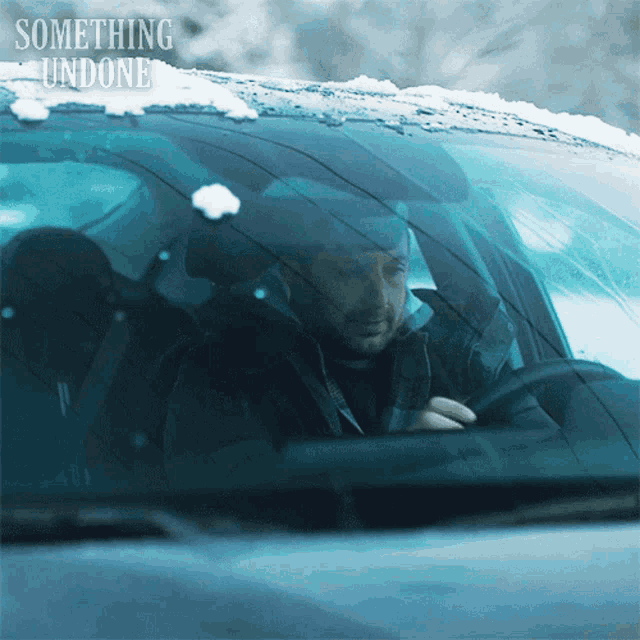 a man in a car with something undone written on the bottom right
