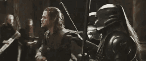 a man in a helmet is fighting another man with a sword .