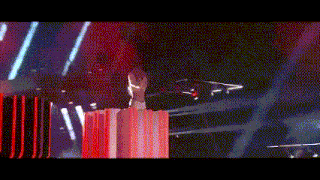 a woman is standing on top of a red box on a stage in a dark room .