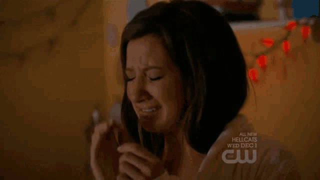 a woman is covering her face with her hands and a cw logo is visible in the corner