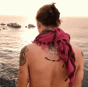 a naked man with a scarf around his neck and a tattoo on his back