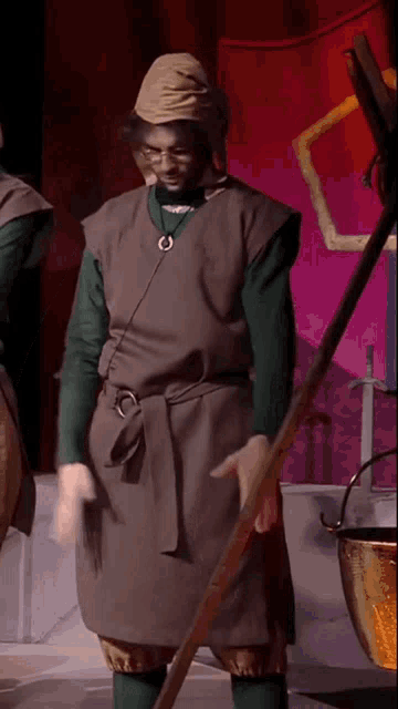 a man in a medieval costume is holding a pole