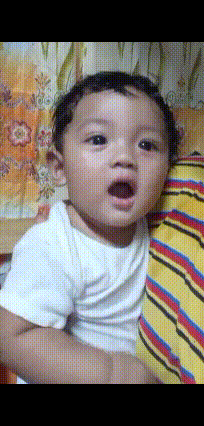 a baby with a surprised look on his face is being held by a person wearing a striped shirt