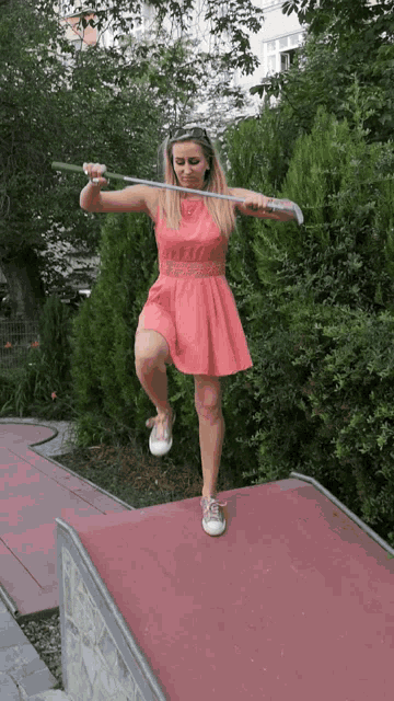 a woman in a pink dress is holding a golf club over her head